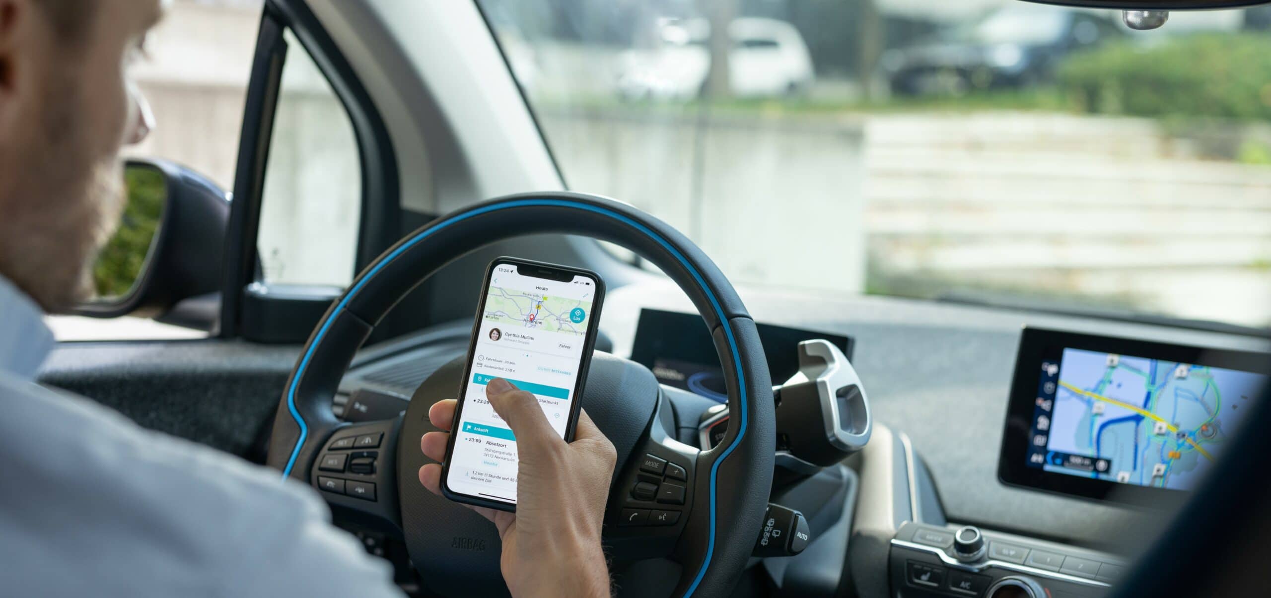 Autofahrer, der die smarte Mitfahrlösung twogo als App auf seinem Smartphone nutzt
